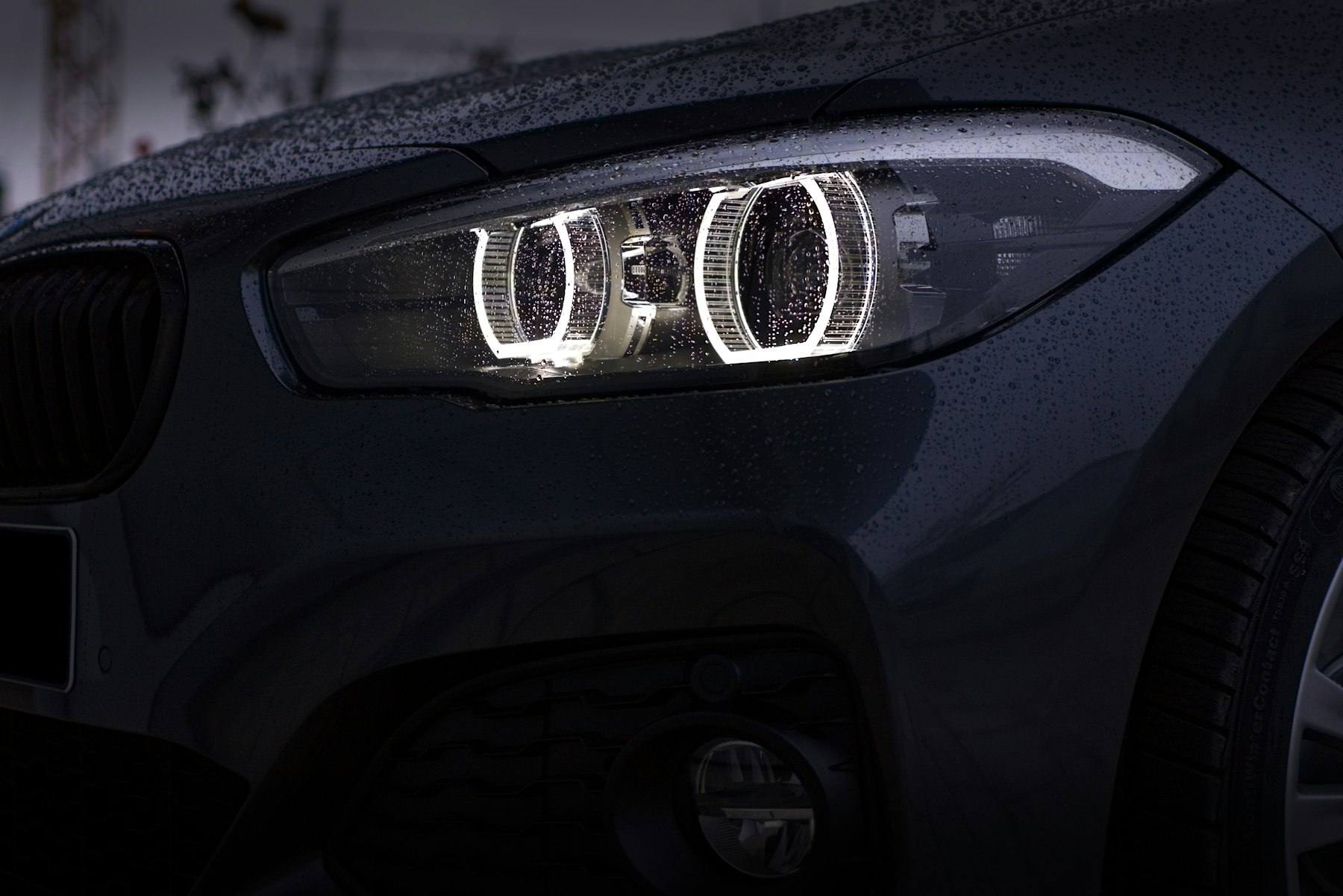 Close-up of a black SUV's headlight and glossy front bumper