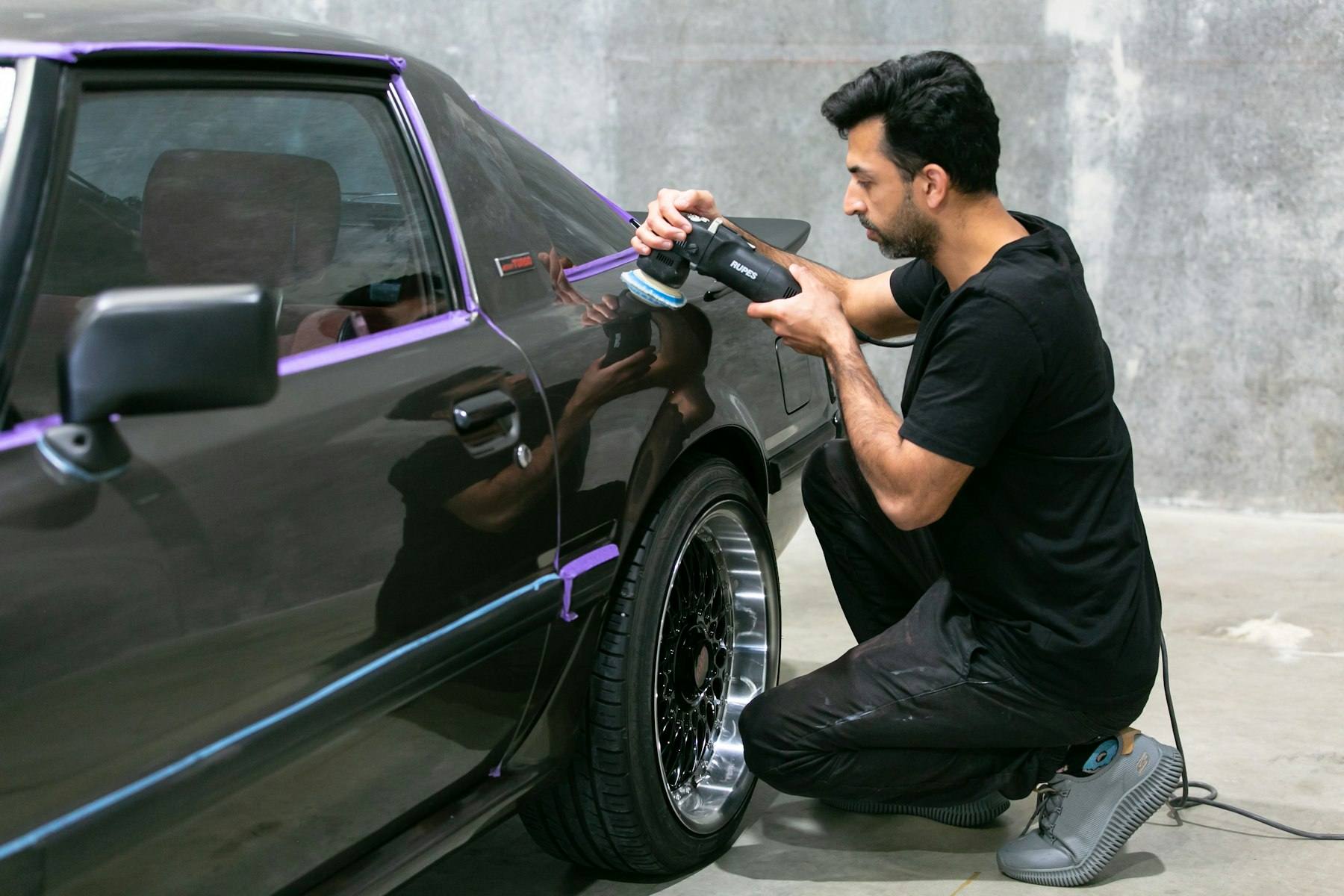 Detailer hand-polishing the paintwork of a classic car