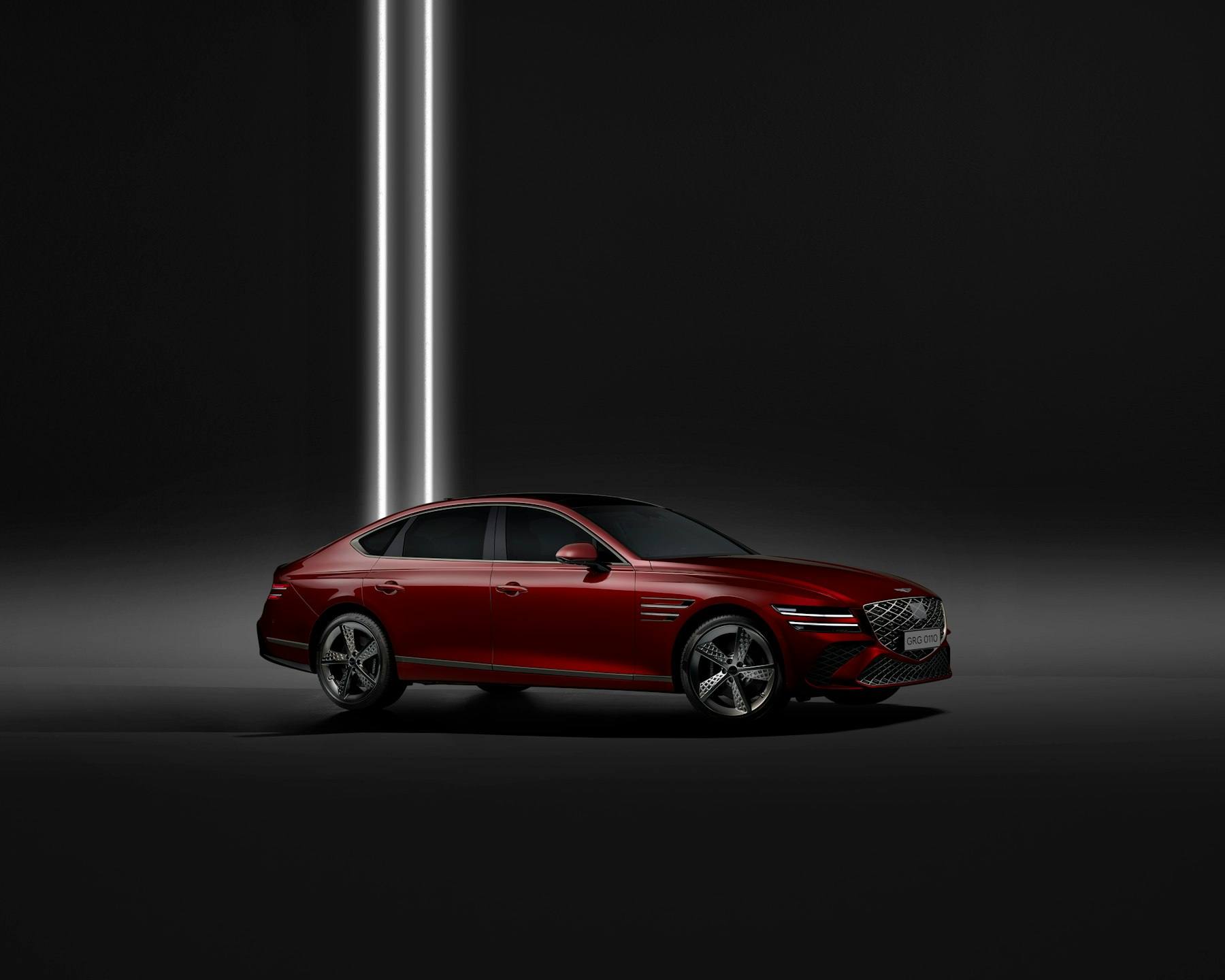 Red sedan under a single studio light